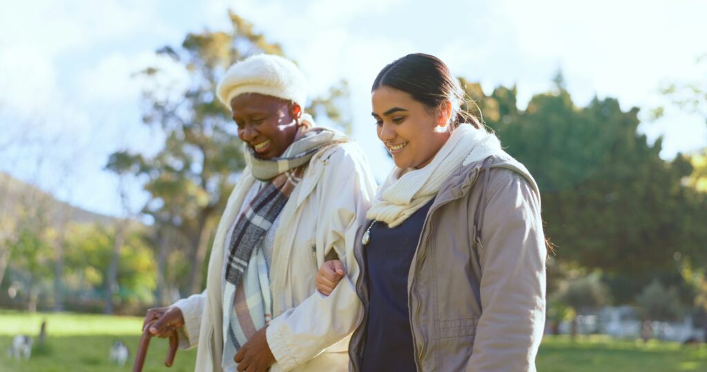 Senior care, old woman with cane and nurse in park with support, help or trust at nursing home. Ret